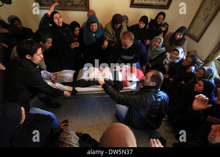 Birzeit, West Bank, Territorio palestinese. 28 feb 2014. Lutto palestinese portano il corpo di Mutaz Washaha, 22, un militante del Fronte Popolare per la liberazione della Palestina (PFLP), dalla Cisgiordania città di Birzeit, a nord di Ramallah, durante il suo funerale 28 febbraio 2014. Mutaz è stato ucciso dalle forze israeliane che presumibilmente utilizzato missili e bulldozer sulla sua casa il 27 febbraio 2014 Credit: Issam Rimawi APA/images/ZUMAPRESS.com/Alamy Live News Foto Stock