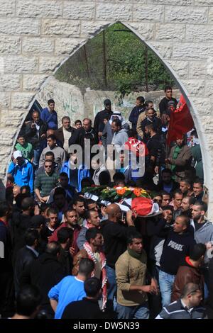 Birzeit, West Bank, Territorio palestinese. 28 feb 2014. Lutto palestinese portano il corpo di Mutaz Washaha, 22, un militante del Fronte Popolare per la liberazione della Palestina (PFLP), dalla Cisgiordania città di Birzeit, a nord di Ramallah, durante il suo funerale 28 febbraio 2014. Mutaz è stato ucciso dalle forze israeliane che presumibilmente utilizzato missili e bulldozer sulla sua casa il 27 febbraio 2014 Credit: Issam Rimawi APA/images/ZUMAPRESS.com/Alamy Live News Foto Stock