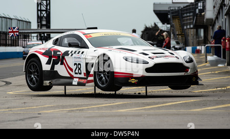 Corse di cavalli e Aston Martin Racing V12 Vantage GT3 auto in piedi nel box, a Donington Park circuito. Foto Stock