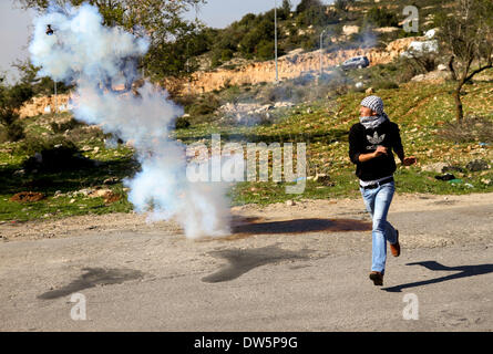 Birzeit, West Bank, Palestina - 28 Febbraio 2014: una gioventù palestinese getta pietre contro soldati israeliani durante scontri al checkpoint di Atara, a nord della Cisgiordania città di Ramallah. Gli scontri scoppiati venerdì dopo il funerale di Muataz Washaha, che è stato ucciso dalle forze israeliane giovedì nella sua casa nella West Bank village di Birzeit, nei pressi di Ramallah. (Foto di Abdalkarim Museitef/Pacific Press/Alamy Live News) Foto Stock