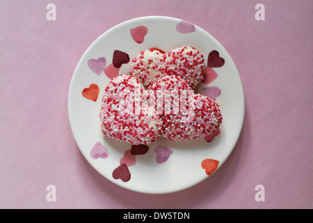 A forma di cuore biscotti shortcake decorate con gusto vaniglia il rivestimento rosso e rosa e bianco zucchero perle su piastra di cuore - ideale per il giorno di san valentino Foto Stock