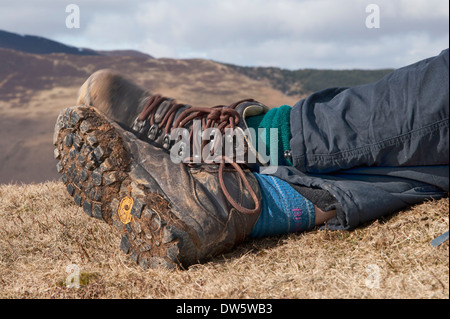 Dettaglio di un camminatore di gambe inferiori come ella poggiano sulla sommità di Barrow, Lake District, Inghilterra. Foto Stock