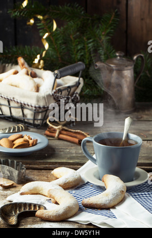 Lo zucchero in casa cookie crescent servita con tazza di tè, vintage accessori, mandorle e spezie su un vecchio tavolo in legno Foto Stock