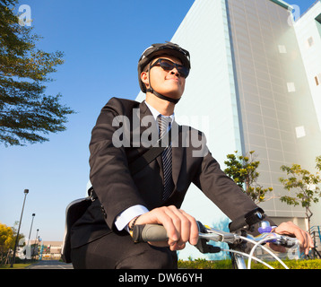 Imprenditore asiatici in sella ad una bicicletta per lavoro in edificio exteior Foto Stock