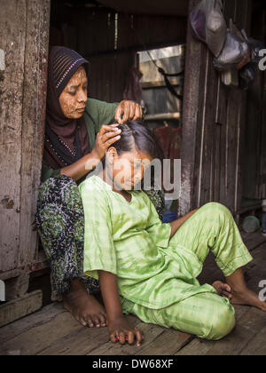 Mae Sot, Tak, Thailandia. 28 feb 2014. Un birmano donna musulmana fissa la figlia della capelli nella loro casa a Mae Sot. Mae Sot, sul Thai-Myanmer (Birmania) frontiera, ha una grande popolazione di immigrati birmani. Alcuni sono i rifugiati che hanno lasciato il Myanmar per sfuggire dei disordini civili e la persecuzione politica, altri sono ''rifugiati economici'' che è venuto in Thailandia in cerca di lavoro e migliori opportunità. © Jack Kurtz/ZUMAPRESS.com/Alamy Live News Foto Stock