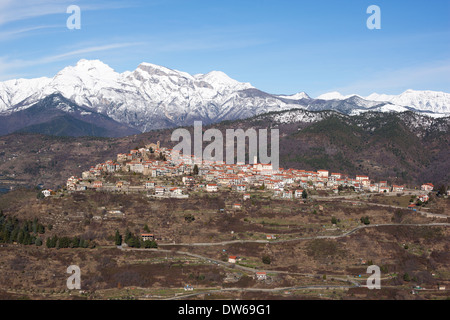 VISTA AEREA. Borgo medievale arroccato con le Alpi innevate all'orizzonte. Bajardo, Provincia di Imperia, Liguria, Italia. Foto Stock