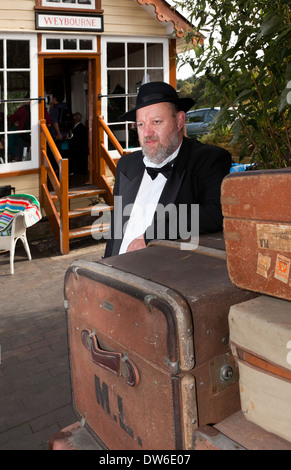 Un uomo in 1940's costume poggiando su alcuni bagagli presso Weybourne stazione ferroviaria Foto Stock