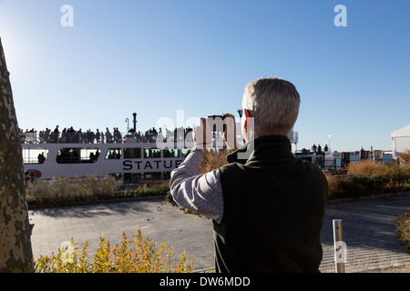 Turismo maturo fotografare la Statua della Libertà del traghetto, Battery Park, New York, Stati Uniti d'America Foto Stock