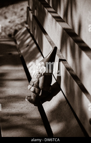 Immagine in bianco e nero di un piccolo gnomo da giardino su un banco di lavoro Foto Stock