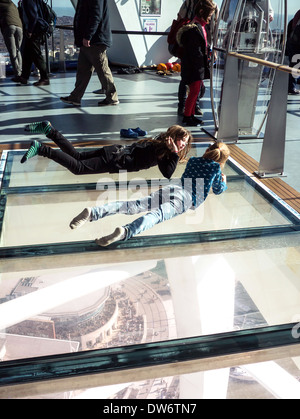 Due giovani ragazze che giacciono sul pavimento di vetro della Spinnaker Tower, Portsmouth, Inghilterra Foto Stock