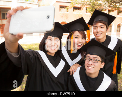 Gruppo di laureati di scattare una foto con il cellulare in campus Foto Stock