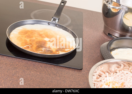 La frittura di frittelle sulla piastra in ceramica Foto Stock