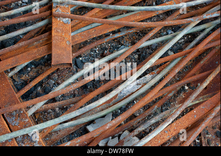 Arrugginite aste di metallo sul pavimento di una bruciò fuori magazzino Foto Stock