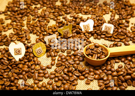 Caffè in grani, caffè-testo e cucchiaino da caffè che illustra tutti gli aspetti del caffè e la produzione del caffè Foto Stock