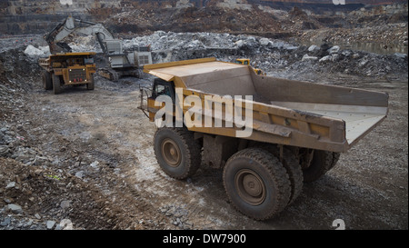 Caterpillar carrello minerario attende in linea mentre un escavatore liebherr minerale di carichi in un camion in background Foto Stock