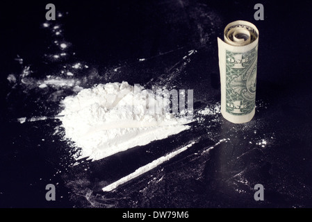 La dose di cocaina e dollaro arrotolato sul tavolo Foto Stock