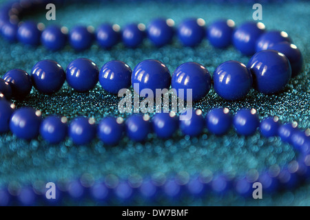 Blu brillante, rotondo, multi dimensioni collana di perle sulla sommità del blu sparkle abito. Foto Stock