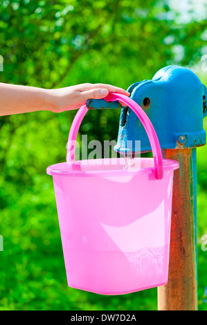 Mano femmina si versa acqua su una colonna in una benna Foto Stock