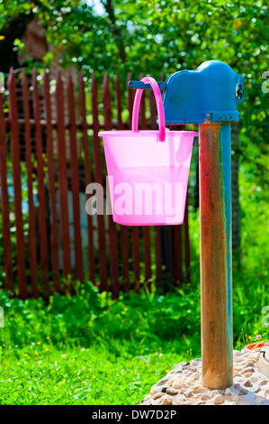 Rosa secchio di plastica e ben rurale Foto Stock