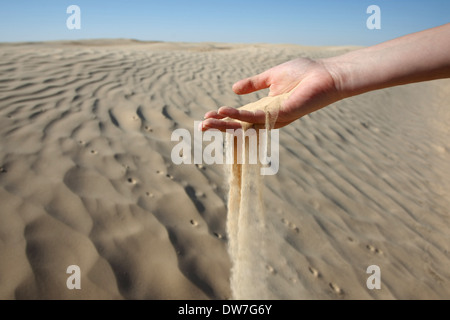 La sabbia scivolare attraverso le dita di una mano di donna il deserto del Sahara in Tunisia. Foto Stock
