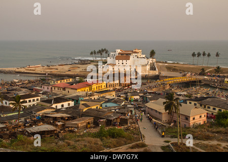 Il castello di Elmina e villaggio di pescatori al tramonto in Elmina, Cape Coast, in Ghana Foto Stock