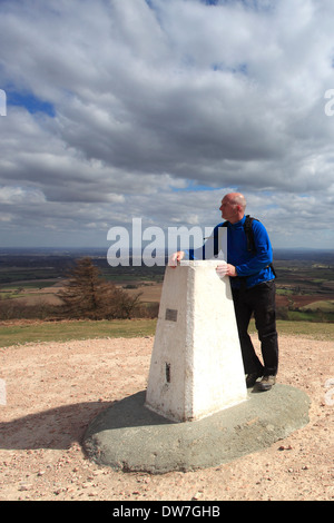 Maschio adulto walker, Bianco Ordinance Survey Trig punto al vertice di Wrekin Hill antico colle fort, Shropshire pianure Foto Stock