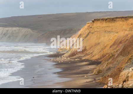 Scogliere, litorale con mare mosso e le onde che si infrangono in maltempo a Compton Bay, Isle of Wight, Tennyson verso il basso dietro Foto Stock