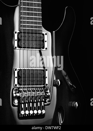 Primo piano artistico di una chitarra elettrica Ibanez con le parti cromate su sfondo nero foto in bianco e nero Foto Stock