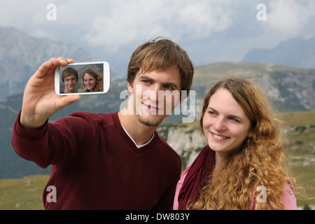 Coppia giovane di scattare le foto con uno smartphone durante le vacanze in montagna Foto Stock