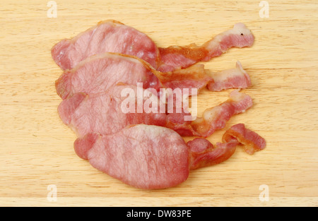 Bacon cotto rashers su una tavola di legno Foto Stock