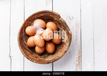 Le uova in una terrina su sfondo di legno Foto Stock