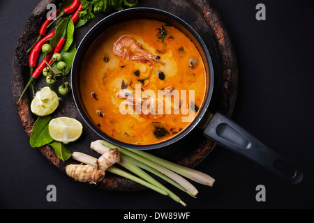 Piccante zuppa tailandese Tom Yam con ingredienti su sfondo scuro Foto Stock