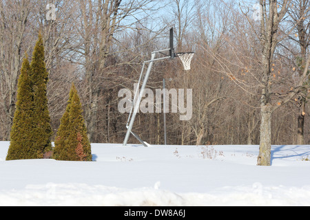 Pallone da basket stand e net su una corte esterno ricoperto di neve Foto Stock