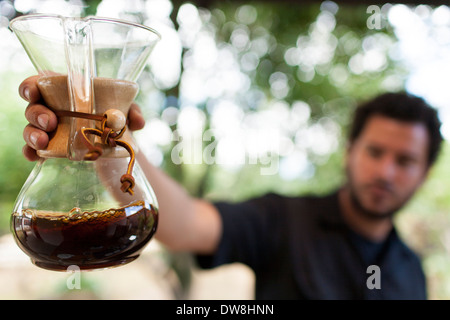 Un El Salvador caffè produttore detiene un pallone Chemex del caffè fresco presso il suo impianto di tostatura in Juayua El Salvador Foto Stock