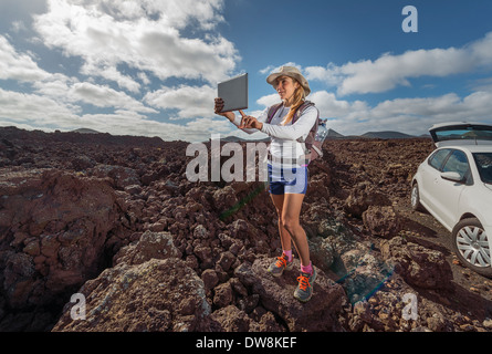 Donna di scattare una foto sul suo digitale compressa. Parco Nazionale di Timanfaya, Lanzarote, Isole Canarie, Spagna. Foto Stock