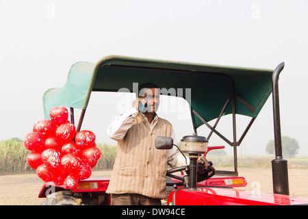 1 L'agricoltore indiano in piedi nella parte anteriore del trattore e parlare Foto Stock