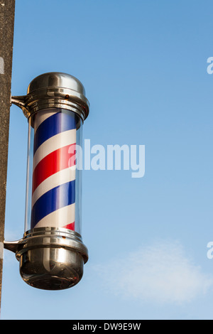 Tradizionale in rosso e bianco del barbiere pole al di fuori di un salone di coiffeur. Foto Stock