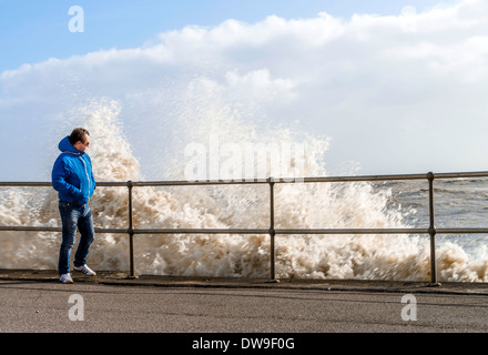 Uomo appoggiato sulla ringhiera al fianco delle onde che si infrangono, Sussex, Regno Unito Foto Stock