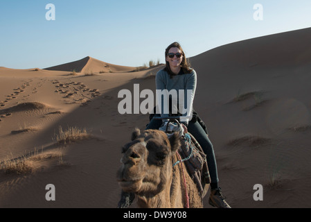 La donna a dorso di un cammello in Erg Chegaga dune del deserto del Sahara, Souss-Massa-Draa, Marocco Foto Stock