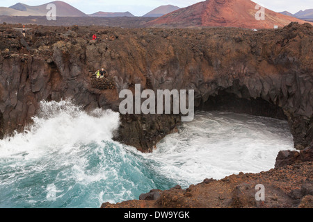 I turisti in una visualizzazione di balcone al di sopra di una grande onda schiantarsi contro scogliere a Costa Los Hervideros Lanzarote isole Canarie Spagna Foto Stock