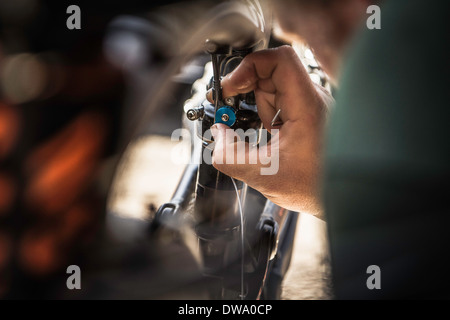 Chiusura del giovane maschio mountain biker riparazione bici Foto Stock