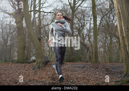 Giovane donna in esecuzione attraverso la foresta Foto Stock