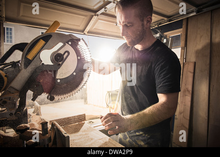 Falegname maschio lavora con una sega rotante in officina Foto Stock