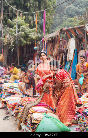 Locali di donne indiane vestite nel tradizionale vivacemente colorato sari vendita di tessuti colorati in un locale mercato stradale Foto Stock