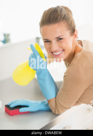 Ritratto di felice casalinga con la bottiglia spray e spugna in bagno Foto Stock