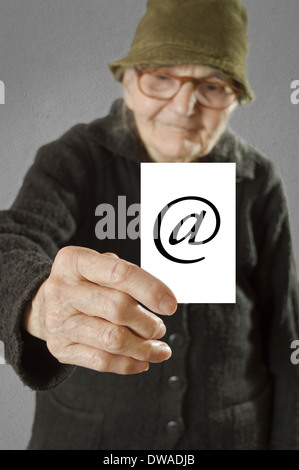 Donna anziana tenendo la scheda con il messaggio di posta elettronica stampato segno. Il fuoco selettivo sulla carta e le dita. Foto Stock