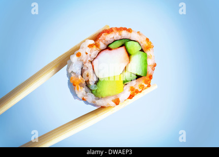 Bacchette azienda sushi gustoso pezzo isolato su sfondo blu, tradizionale giapponese con farina di pesce crudo e riso Foto Stock