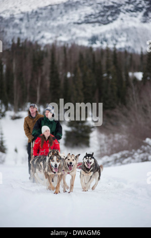 Foto di tre persone di equitazione in slitta trainata da cani in Alaska Foto Stock