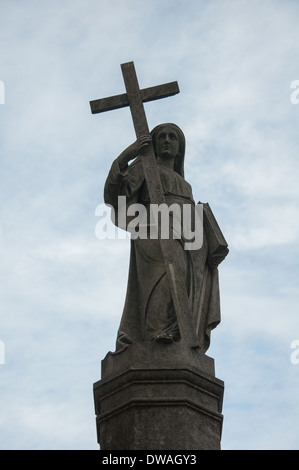 Statua di donna che mantiene una croce e una Bibbia. È la parte superiore di un deposito a Prazeres cimitero nel Campo de Ourique, Lisbona. Foto Stock