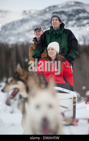 Foto di tre persone di equitazione in slitta trainata da cani in Alaska Foto Stock